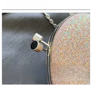 Close-up of champagne pink sequined evening clutch bag with silver metal clasp and chain
