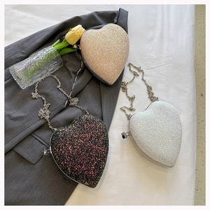 Detailed view of heart-shaped sequin bags in champagne, black and white with silver chains