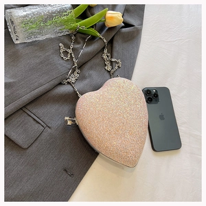 Detail of champagne gold heart-shaped evening bag with glitter texture and chain strap