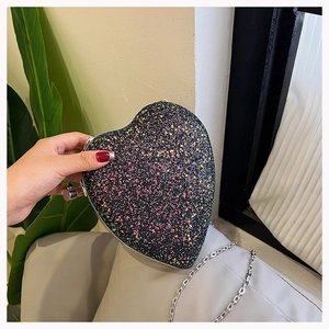 Close-up of heart-shaped evening bag with colorful glitter surface and silver chain strap