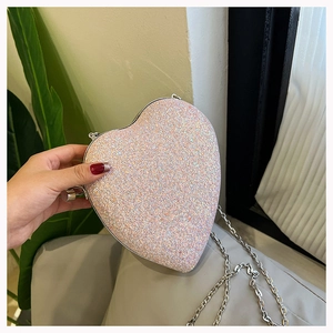 Detail of heart-shaped evening bag with iridescent pink sequins and silver metal chain