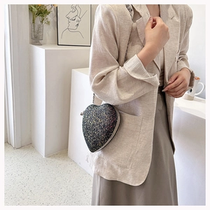 Detail of heart-shaped sequin crossbody bag with colorful glitter and metal chain strap