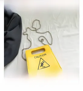 Detail of yellow caution sign handbag with cat print and silver ball chain strap