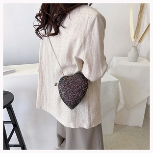Sparkling heart-shaped sequin crossbody bag with chain strap shown on a model