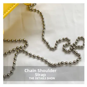 Close-up of polished silver metal bead chain strap on yellow leather crossbody bag