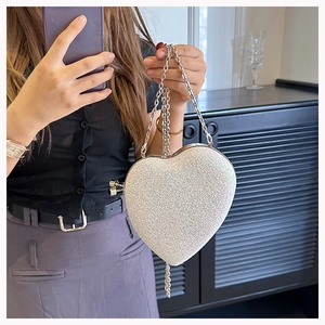 Detail of silver glitter heart clutch bag with metal chain and spherical snap closure