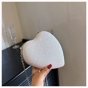 Detailed shot of silver heart-shaped glitter evening bag with fine metal chain strap