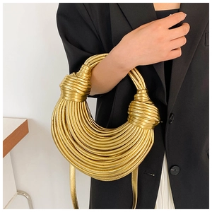 Close-up of golden woven handbag with large decorative knots and shiny metallic texture