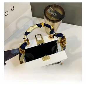 Detail showing internal compartment of a white box bag with gold chain strap