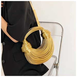Close-up of golden crescent bag with spiral weave and knot detail in modern setting