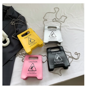 Detail view of four mini crossbody bags shaped like caution signs in vibrant colors