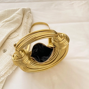 Detail of gold metallic woven handbag featuring a distinctive knot handle and zip closure