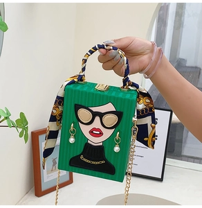 Detail of green box bag with portrait design, silk-wrapped handle and gold chain strap