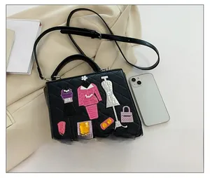 Close-up of black quilted handbag with fashion embroidery patches and size comparison