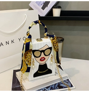 Detail of white box bag with fashion illustration, gold lock and printed scarf handle