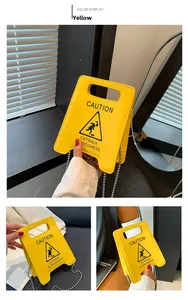 Detail of yellow Caution sign chain bag featuring Catwalk In Progress print and silver chain