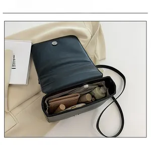 Internal capacity of black leather crossbody bag showing inner pocket and storage space