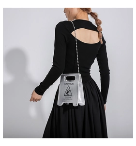 Silver caution sign shoulder bag with bead chain strap shown on a model's back