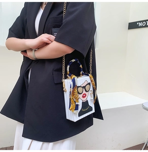 Detail of white box clutch bag featuring cartoon portrait and silk scarf handle