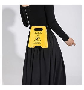 Close-up of yellow Caution sign handbag with metallic chain strap and Catwalk text