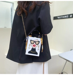 Detailed view of a white box bag with a cartoon portrait and a silk scarf on the handle