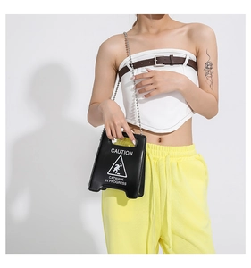 Detail of creative black handbag with caution sign print and silver bead chain strap