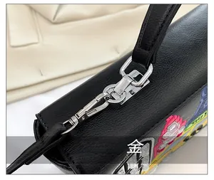 Detail of black pebbled leather handbag with silver hardware and colorful embroidery