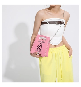 Detailed view of pink caution sign crossbody bag with Catwalk In Progress print design