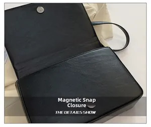Detail view of the magnetic closure and pebbled leather texture on black shoulder bag