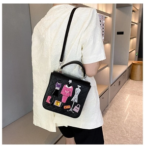 Detail of black quilted crossbody bag with stylish fashion-themed embroidery and gems