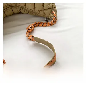 Détail du sac matelassé kaki avec poignée tressée orange et bandoulière en cuir