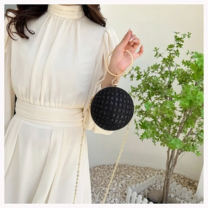 Detailed view of spherical evening bag with black shimmer texture and gold ring handle