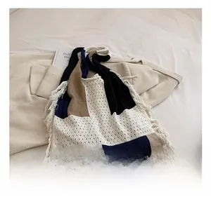 Detail of color-block knitted tote bag with long tassels in a minimalist lifestyle setting