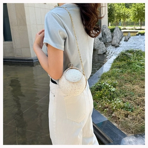 Detail of white glitter round evening bag with gold metal frame and delicate chain strap