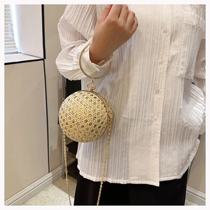 Detail of a sparkling gold spherical evening bag with rhinestones and metal ring handle