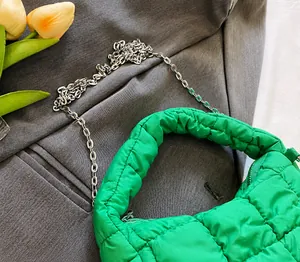 Detalle de bolso acolchado verde brillante con cadena plateada y cierre de cremallera