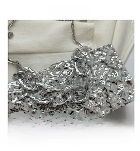 Detailansicht der silbernen Flüssigmetalltextur und Kette der Acryl-Box-Tasche