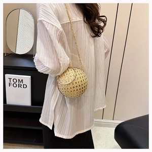Macro detail of sphere woven evening bag with gold chain strap and metal handle