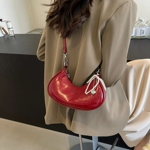Red glossy half-moon underarm bag with pearl chain and heart charm in a trendy crossbody style