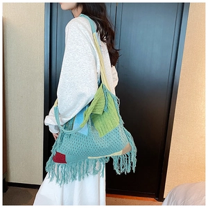 Close-up of colorful crochet tote bag with long bohemian tassels and mixed knit patterns