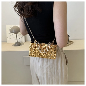 Detail der goldenen Acryl-Box-Tasche mit Faltenstruktur und schicken Kettenriemen