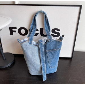 Detail shot of blue denim patchwork tote bag with pocket on a minimalist studio desk