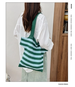 Detail of green and blue striped knit tote bag styled with white shirt and denim skirt