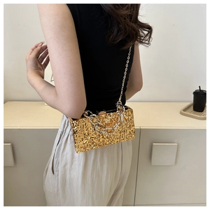 Detail der goldfarbenen Clutch mit Lava-Struktur und grober Kette an der Schulter
