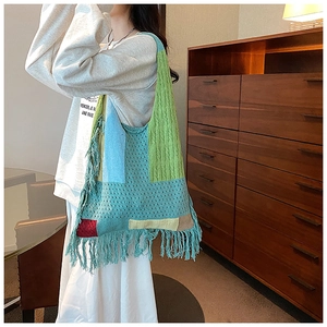 Detail of colorful patchwork knit tote bag featuring fringe accents and boho style texture