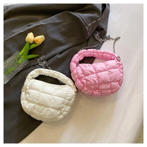 Detalle de bolsos acolchados blancos y rosas con correas sobre chaqueta gris
