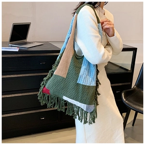 Detail view of colorful knit tote bag featuring bohemian tassels and multi-color patchwork