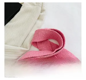 Detail showing the pink knitted handle attached to a beige ribbed tote bag texture