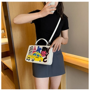 Mirror selfie showing a white crossbody bag with NYC themed embroidery and taxi patch