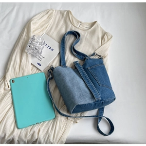Close-up of dual-tone denim patchwork shoulder bag with adjustable strap and front pocket